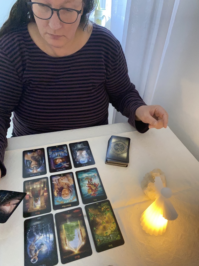 tarotkort utlagda på bordet framför en kvinna som läser dem